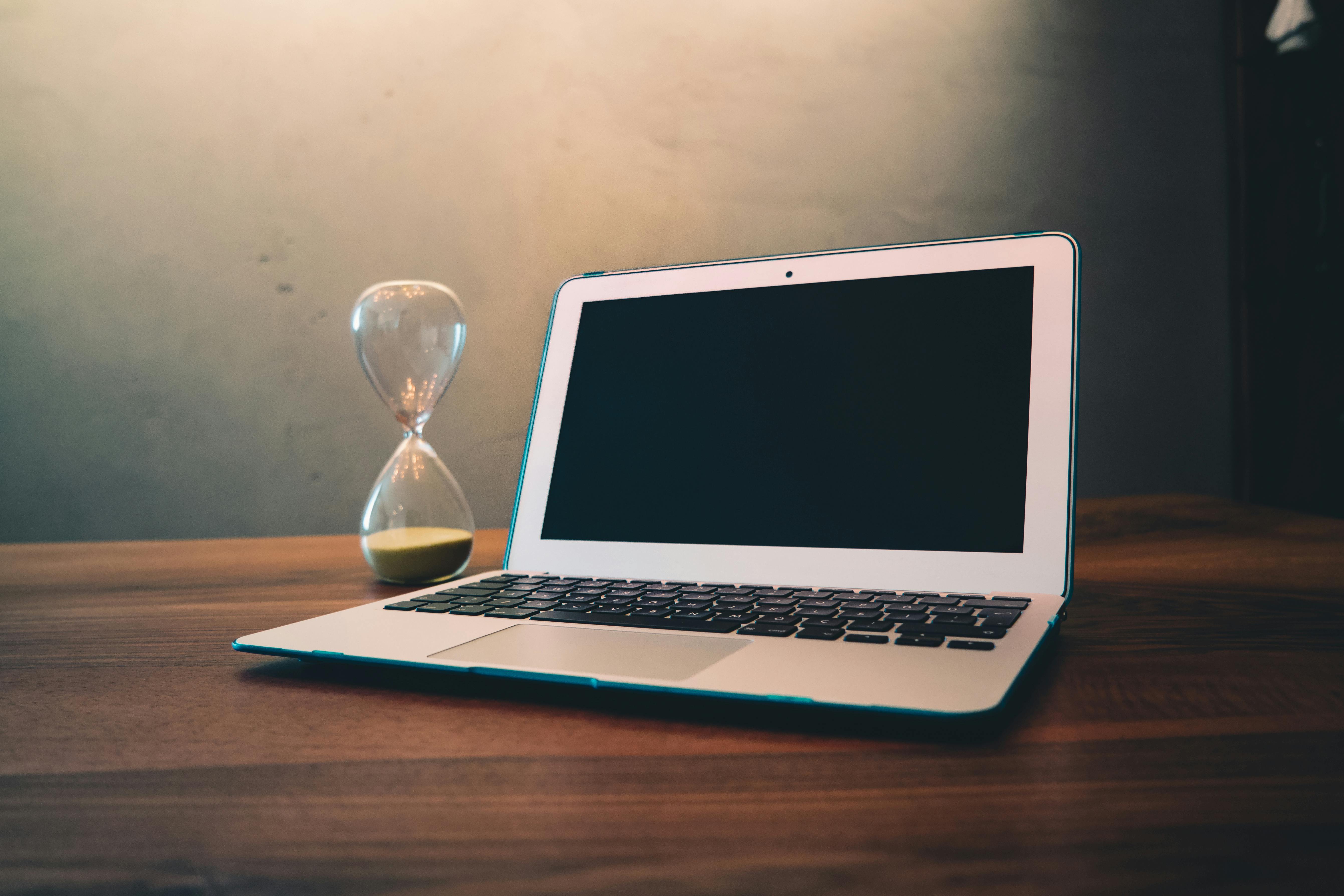 Laptop beside an hourglass, illustrating slow-loading pages and wasted visitor patience